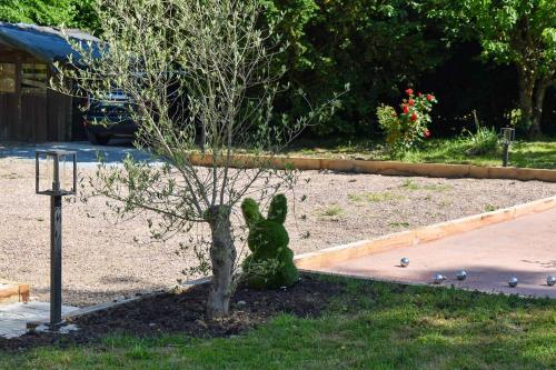 a statue of a rabbit sitting next to a tree at Au Clos de la Bergerie - campagne, détente & pétanque in Pont-lʼÉvêque