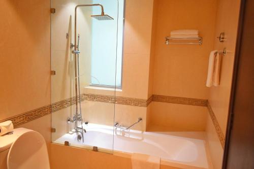a bathroom with a tub and a glass shower at Saraya Corniche Hotel in Doha