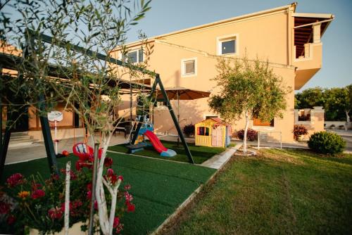 un patio con parque infantil frente a una casa en Al Mare Family Suite, en Mólos