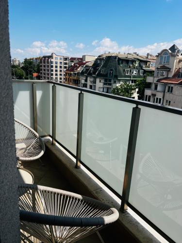a balcony with two chairs and a view of a city at Heart & Honey - The Romantic Loft in Plovdiv