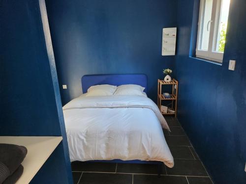 a blue bedroom with a bed with a blue wall at Petit appartement de charme in Saint-Pierre-lès-Nemours