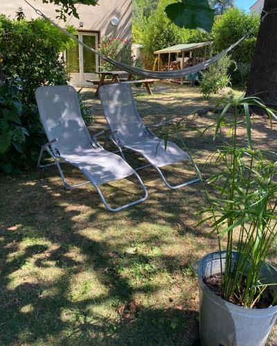 two empty chairs sitting in the grass in a yard at Bel appartement avec jardin in La Bégude-de-Mazenc