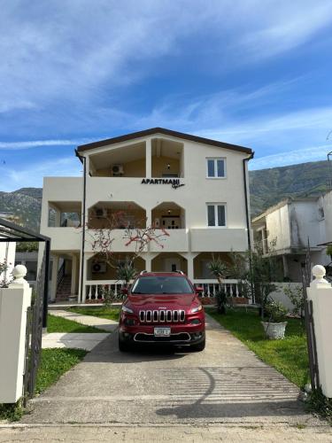 a red car parked in front of a building at Apartmani Rira in Sutomore