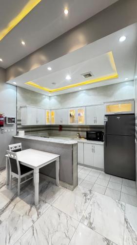 a large kitchen with a table and a refrigerator at شاليه ريف المملكة in Hail