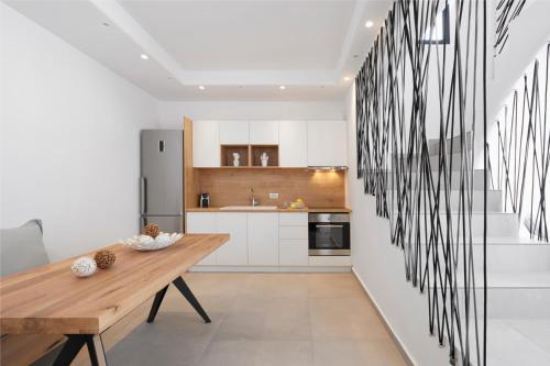 a kitchen with white cabinets and a wooden table at Amor Hideaway Villas in Fira