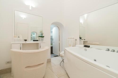 a white bathroom with a tub and a large mirror at Villa Magia in Positano