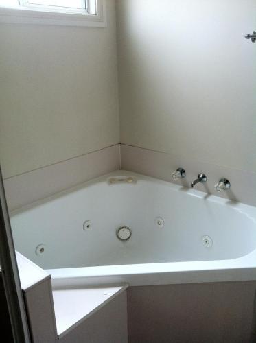 a bath tub with two faucets in a bathroom at Edgewater Holiday Park in Port Macquarie
