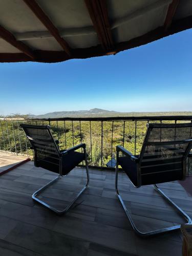 two chairs sitting on a deck with a view at Little tree house in Kiserian