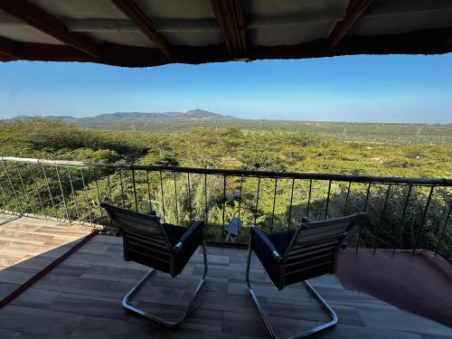 two chairs sitting on a balcony with a view at Little tree house in Kiserian
