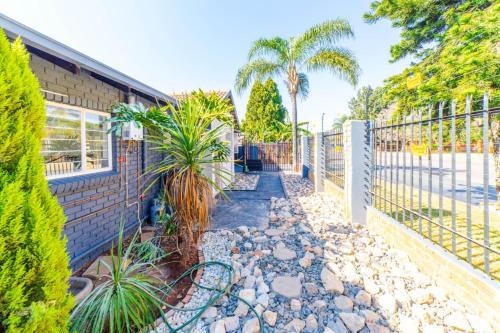 a fence next to a house with palm trees at Homes of Ace Executive in Pretoria