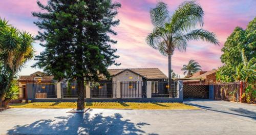 a house with palm trees and a fence at Homes of Ace Executive in Pretoria