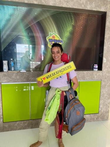a woman is holding a sign that reads maximize surprises at Female Hostel wakakapacker in Kuala Lumpur