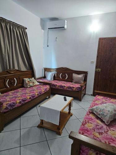 a room with three beds and a table in it at Casa blu ghar el melh in Île Pilau