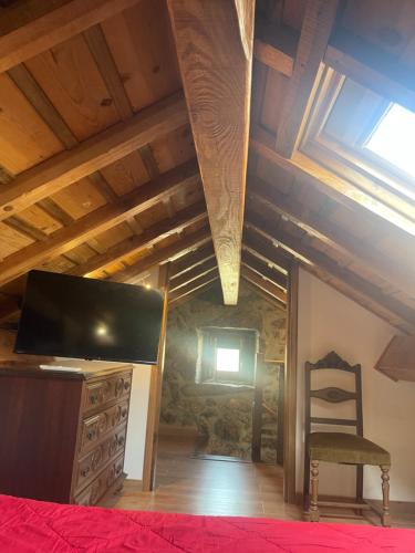 a bedroom with a bed and a tv and a chair at Casa Pinhão in Sabugueiro