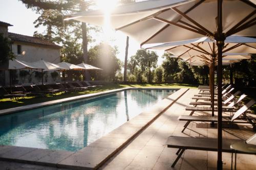 a swimming pool with chairs and umbrellas next to it at La Pescaia Resort in La Pescaia
