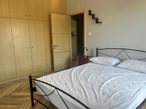 a bedroom with a white bed and a closet at Kampos Apartment in Chios