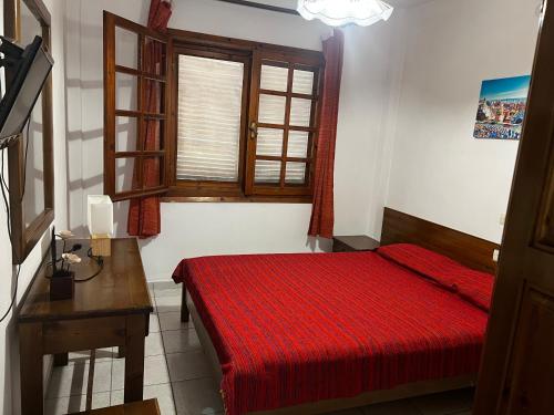 a bedroom with a red bed and a window at Traditional Bungalows in Kalyves Poligirou