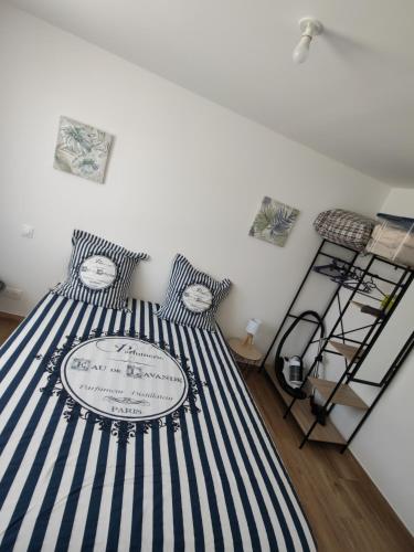 une chambre avec un lit à rayures bleues et blanches dans l'établissement Appartement spacieux 3 chambres SAINT PIERRE LA MER, à Saint Pierre La Mer