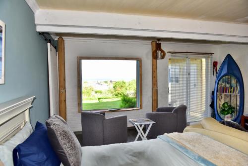 a bedroom with a bed and chairs and a window at Seaview on 2822 Happy Whale Cottage in Bettyʼs Bay