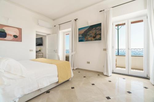 a white bedroom with a bed and large windows at Villa Magia in Positano