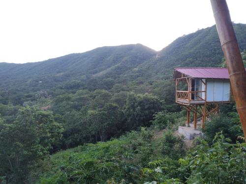a house on a hill with mountains in the background at El Eden Glamping cabañas Girardot in Girardot