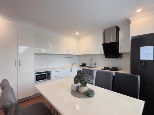 a kitchen with white cabinets and a table with a plant on it at Family Haven in Sunnybank with 2BR 2Bath 3 Beds in Brisbane