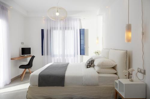a white bedroom with a bed and a chair at Amor Hideaway Villas in Fira