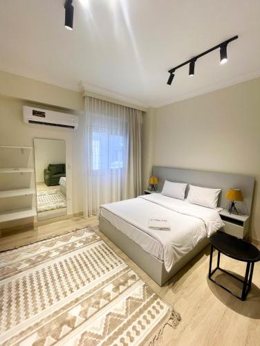 a bedroom with a large white bed and a window at Settle Inn Rawda Apartments in Cairo