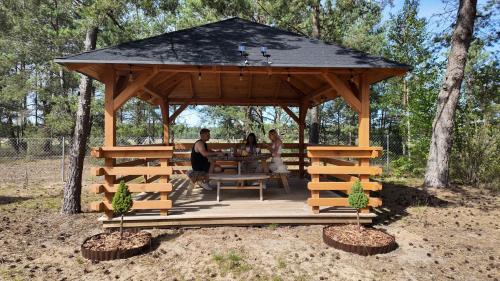a wooden gazebo with people sitting at a table at Chatki na Kaszubach in Borsk