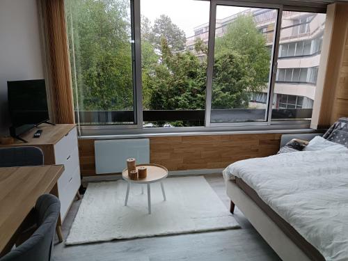 een slaapkamer met een bed, een tafel en ramen bij Se détendre Au Petit Epi in Turckheim