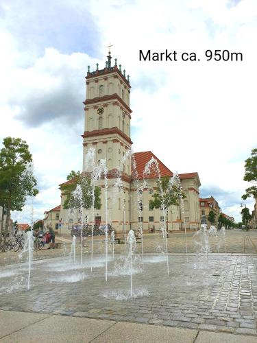 a building with a clock tower in front of a fountain at Ferienwohnung Viona in Neustrelitz