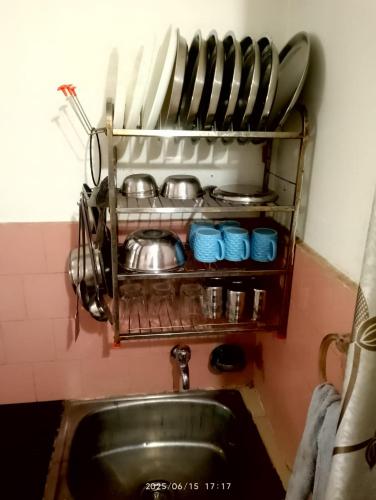 a kitchen with a sink and a shelf with pots and pans at Amazing Homestay in Guwahati