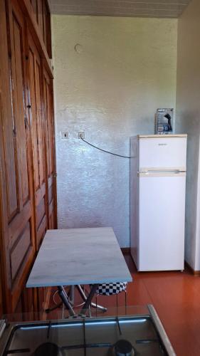 a kitchen with a table and a white refrigerator at სახლი ბუნებაში House in nature in Tsikhisdziri