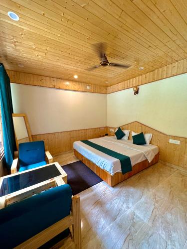 a bedroom with a bed and a chair in it at Hotel Mid Orchard Kasol l River Side -Pure Veg Hotel in Kasol