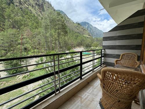 a balcony with two chairs and a view of a river at Hotel Mid Orchard Kasol l River Side -Pure Veg Hotel in Kasol