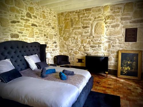une chambre avec un lit et un mur en pierre dans l'établissement Le Domaine de Pépé, à Saint-Julien-de-Briola