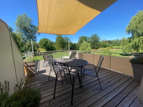 a patio with a table and chairs on a deck at La Maison au Vert in Melincourt