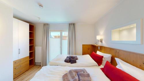a bedroom with two beds with red pillows at Haus Ostwind OSTWIND 'Groot Pläseer' in Langeoog