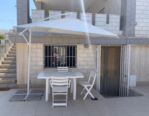 a table and chairs on a patio with an umbrella at Dimora Terra di Puglia in Torre Santa Sabina