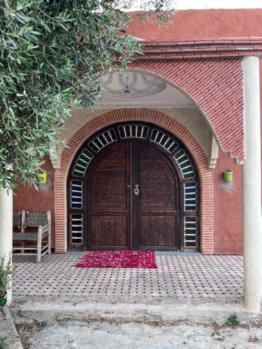 a large wooden door with red flowers in front of it at Riad de luxe à safi in Safi