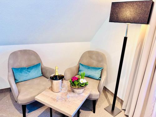two chairs and a table with a lamp and flowers at Inselsünn Hotel und Apartments in Spiekeroog