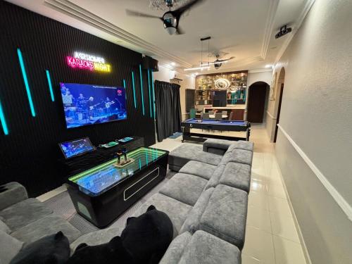 a living room with a large couch and a tv at Kulai Neon Bliss Villa in Kulai
