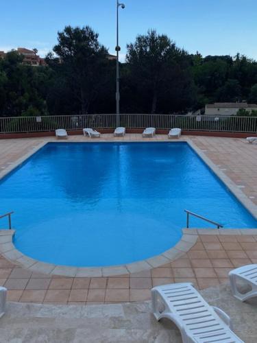 une grande piscine bleue avec deux chaises longues dans l'établissement Le Sénèque - Fréjus - Piscine, à Fréjus