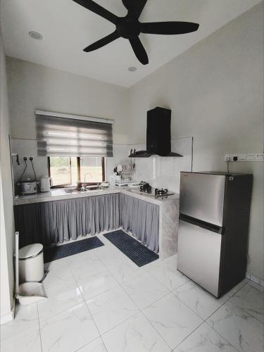 a kitchen with a refrigerator and a ceiling fan at Homestay De'daun kulim mus'lim only in Kulim