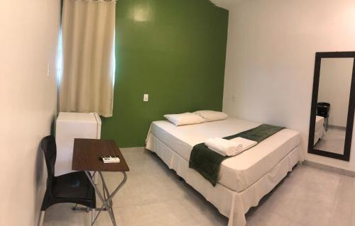 a bedroom with a bed and a table and a mirror at Hotel do Hulk in Barreirinhas