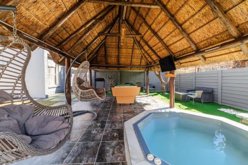 a patio with a hot tub and wicker chairs at Homes of Ace 3 bedroom Villa in Pretoria