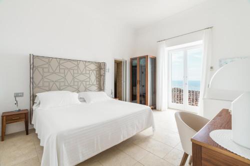 a white bedroom with a large bed and a window at Villa Magia in Positano