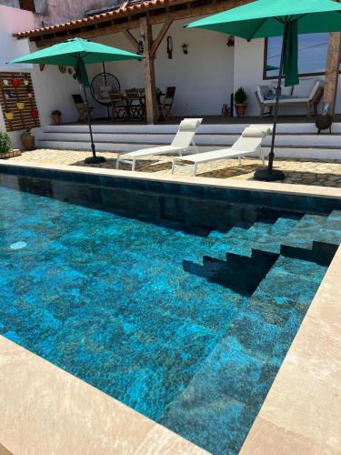 a swimming pool with chairs and umbrellas in it at Cantinho da Villa in Portel