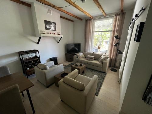 a living room with couches chairs and a tv at B&B appartement Rebel and Moon in het centrum van Alblasserdam in Alblasserdam