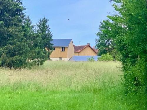 a large field of grass with a house in the background at La scierie Massonat in Cossaye